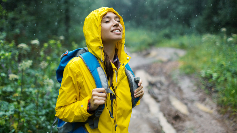 A young woman in a yellow raincoat enjoy the rain.