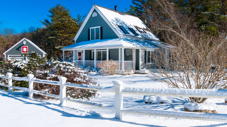 A house and yard are covered in freshly fallen snow.