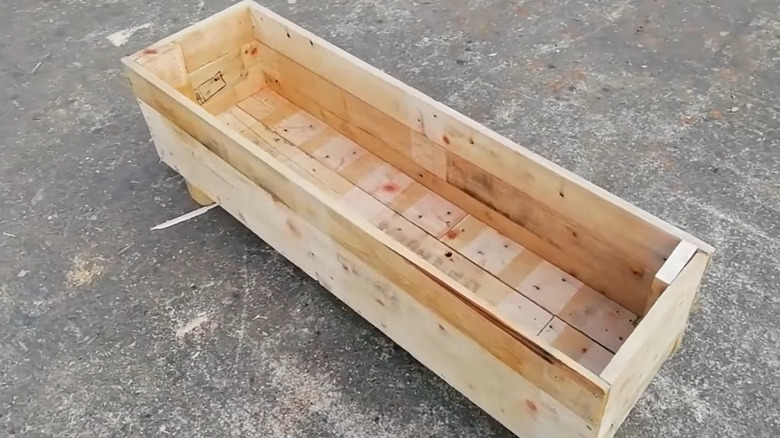 A man creates a planter out of a pallet.