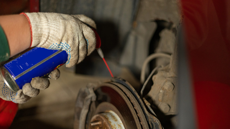 Man sprays WD-40 on a rusted tool.
