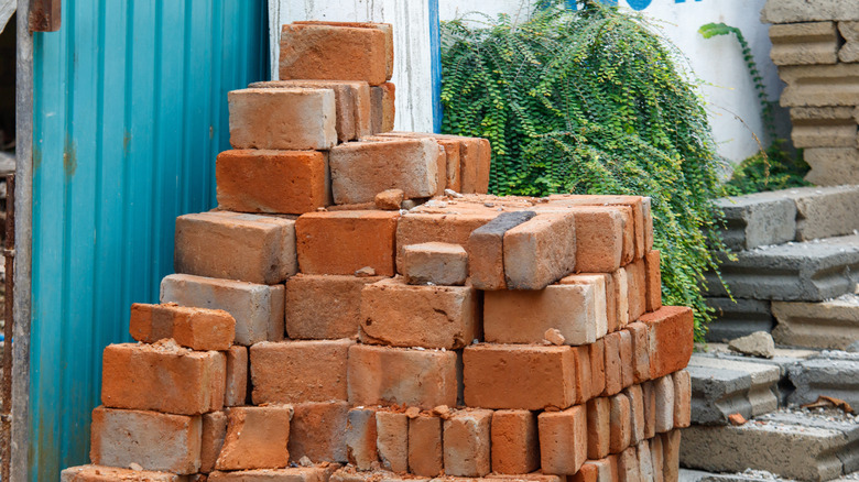 A pile of old orange-brown bricks sit against a building.
