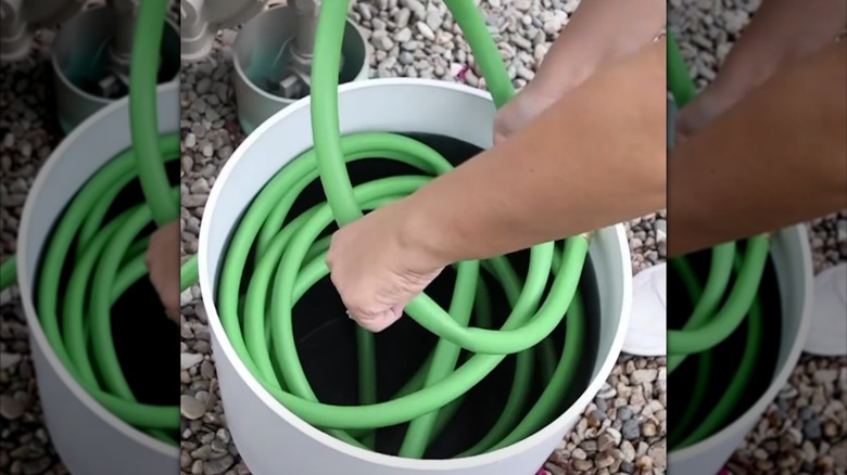 A woman stores her garden hose in a planter.