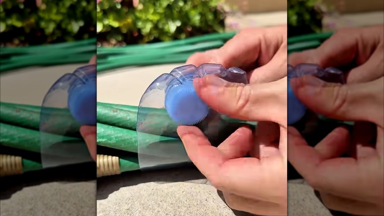 A person uses a cut soda or water bottle to keep their hose neatly rolled up.