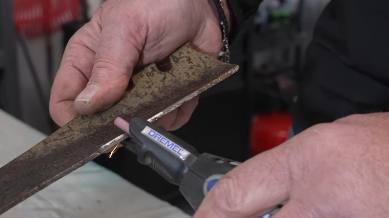 A Dremel tool is used to sharpen a lawn mower blade.