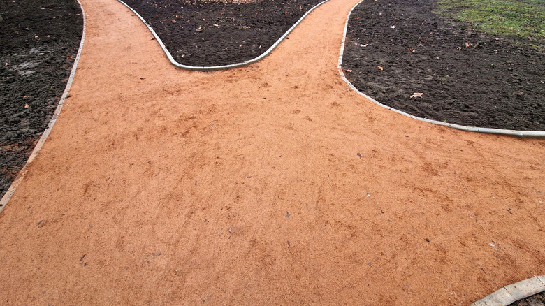 A newly constructed reddish decomposed granite path lined with concrete bricks