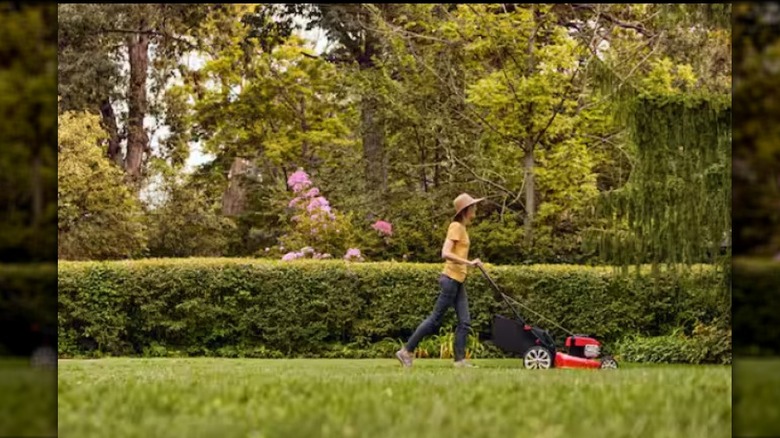 A red and black Troy-Bilt TB110 mower being pushed by a woman