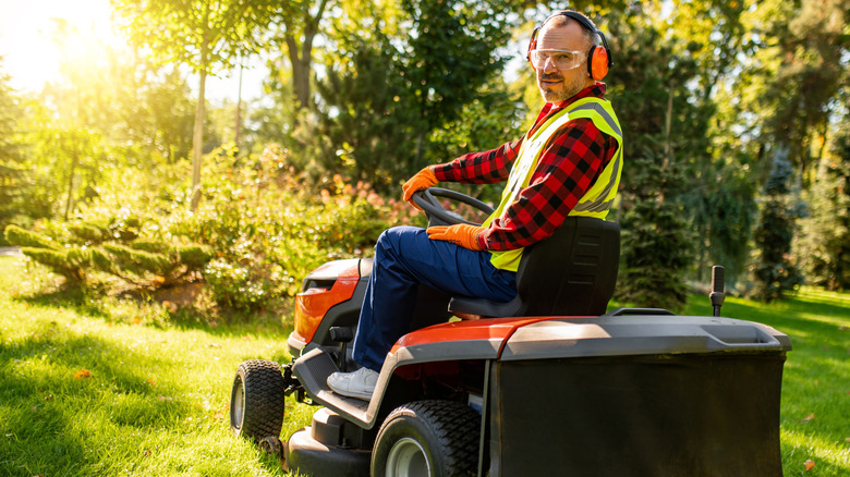 A man sits on a ride-on mower.