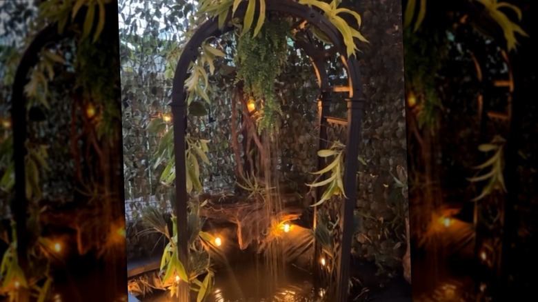 A water feature boasts a trellis with water falling from it.