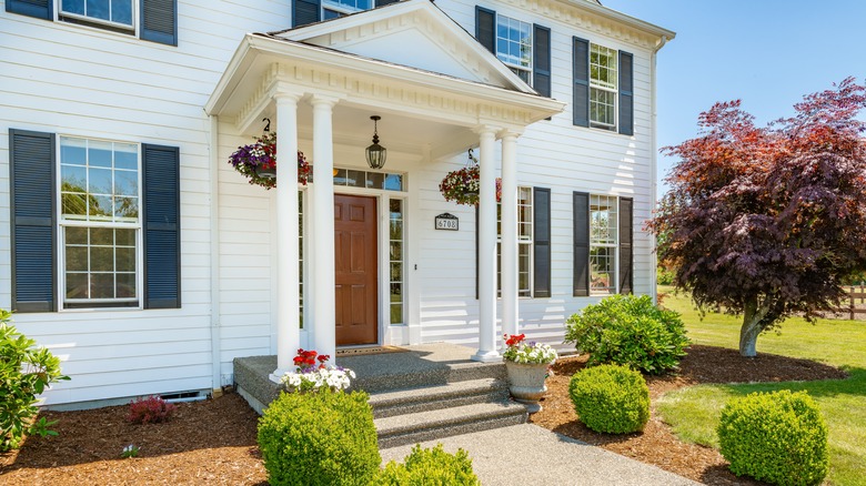 A home boasts symmetrical planters and shrubs in their front yard.