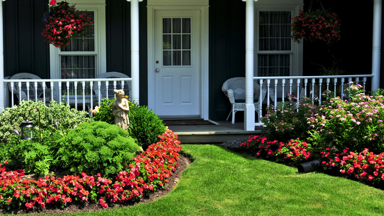 Flowers and manicured shrubs grow in front of a house.