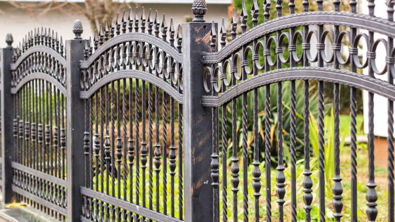 A garden boasts an elegant wrought iron fence.