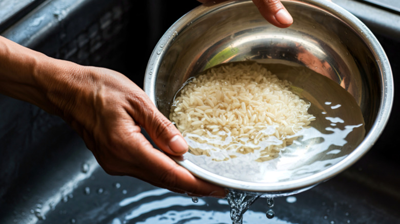 Woman washes uncooked rice in a bowl.
