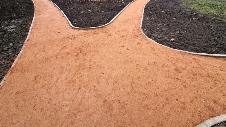 A newly constructed reddish decomposed granite path lined with concrete bricks