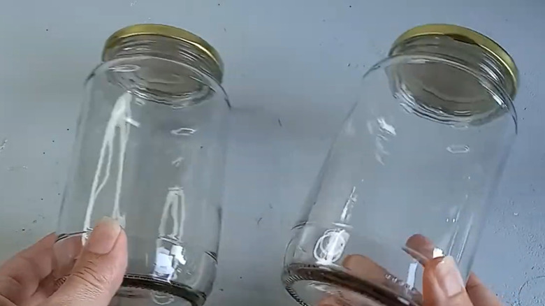 A woman holding two empty glass jars.