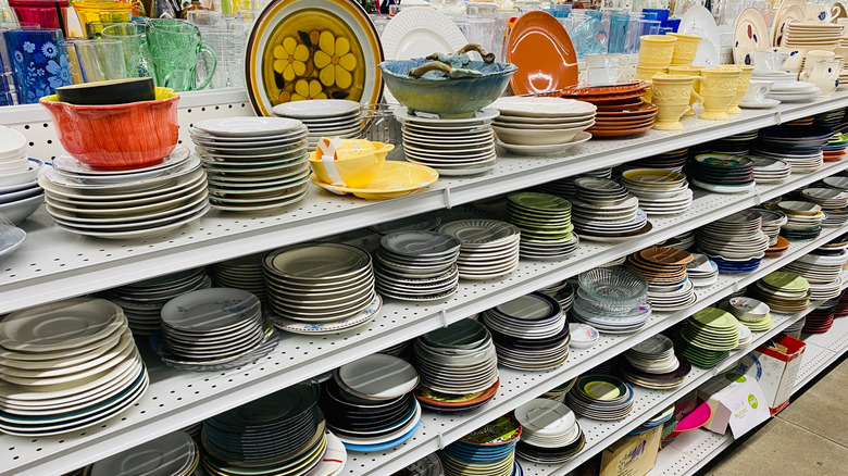 Piles of dishes line the shelves of a thrift store.