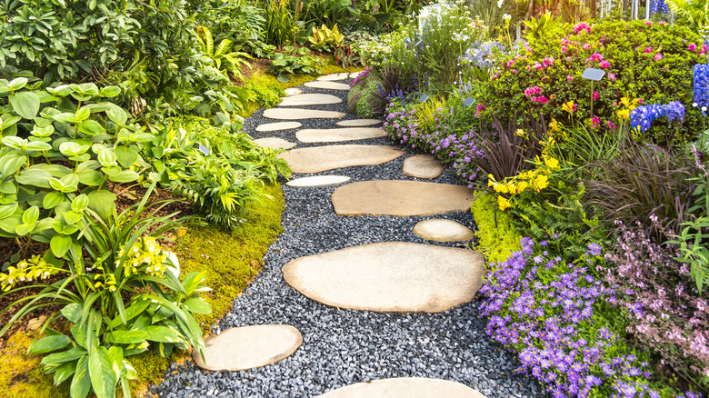 A path made of stepping stones curves through a flower garden.