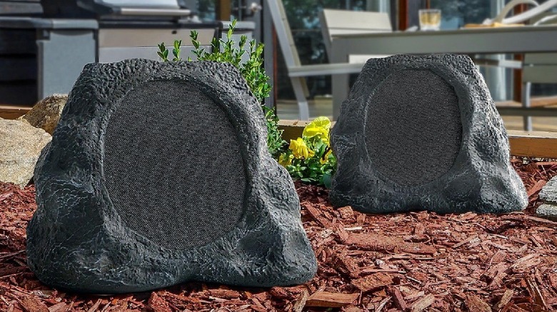 Victrola outdoor rock speakers sit in flower bed.