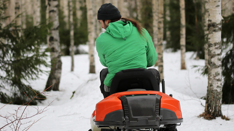 Man rides his lawn mower over snow.