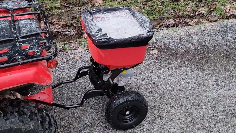A seed spreader attachment is filled with rock salt for snow.