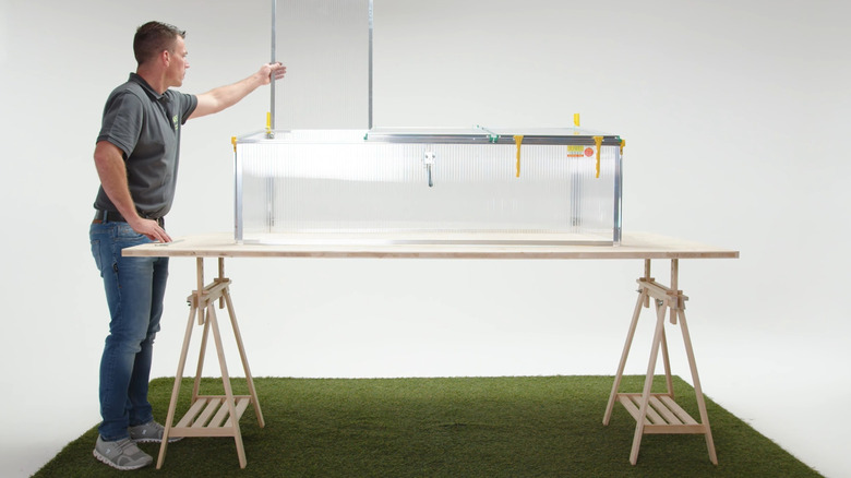 A man opens the hatch of a Juwel Biostar 1500 mini greenhouse.