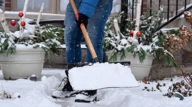 Person shovels snow off a porch.