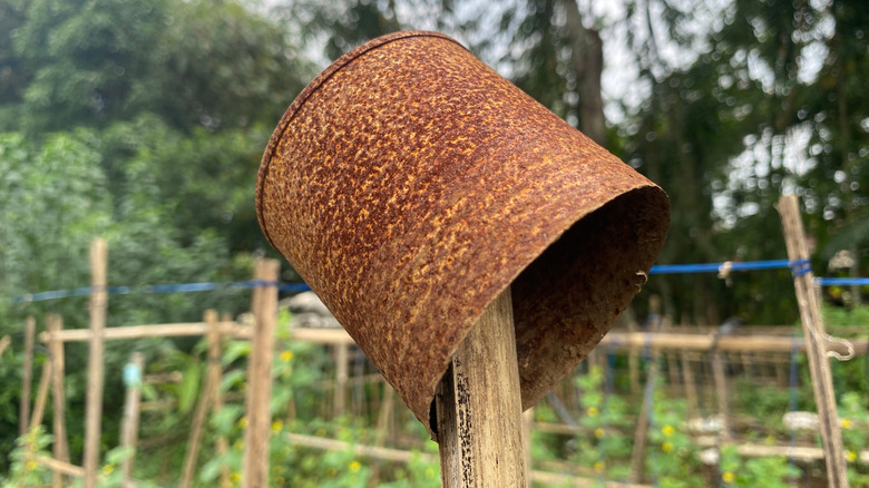 A metal pot is upside down on top of a garden stake.
