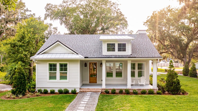 A white home is surrounded by trees of different heights.